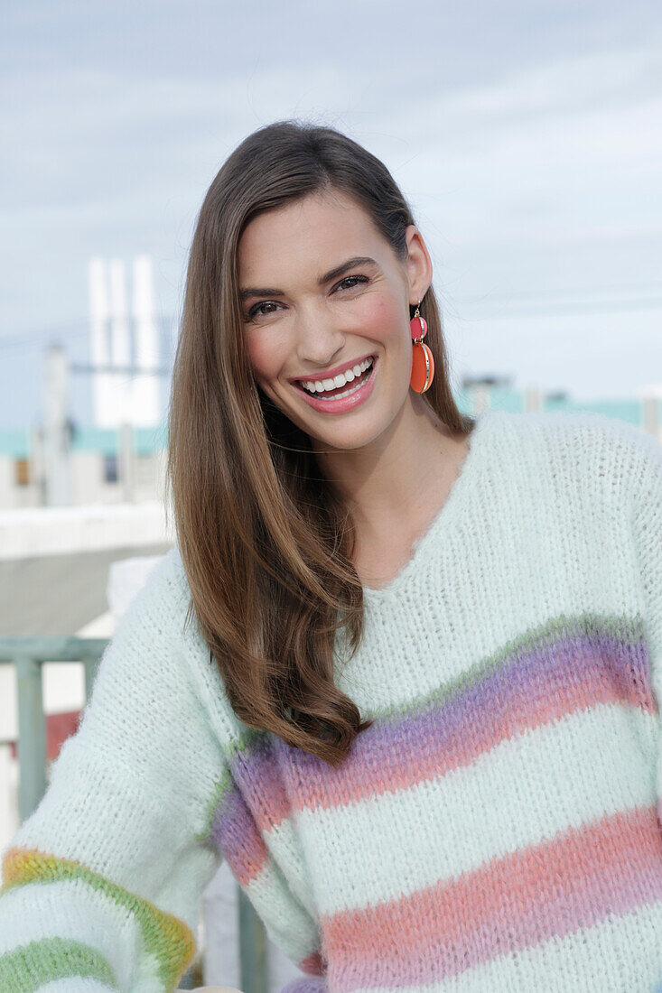 Young woman wearing a light knitted jumper with colorful stripes