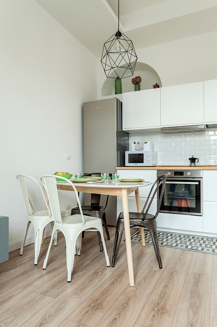 Small dining area with classic chairs in front of white kitchenette