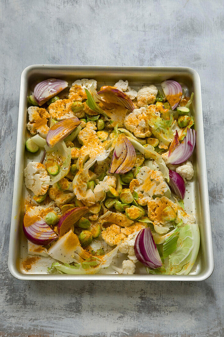 Cauliflower florets with red onions and turmeric in a roasting tin