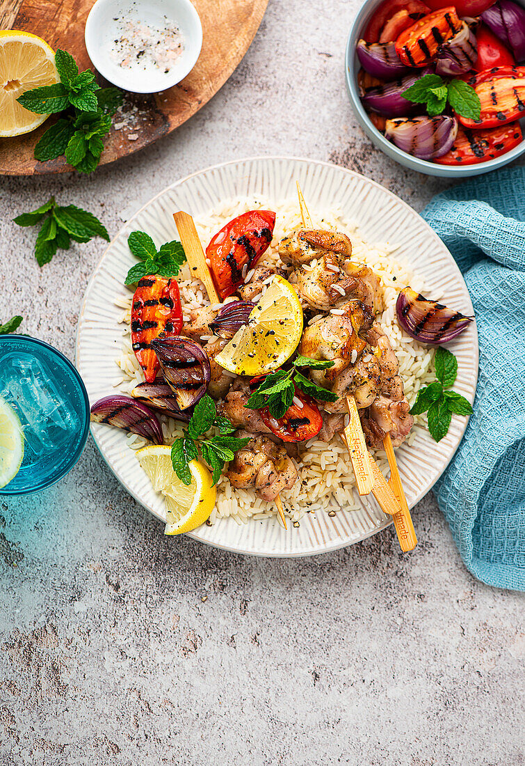 Grilled chicken skewers with peppers and red onions on rice