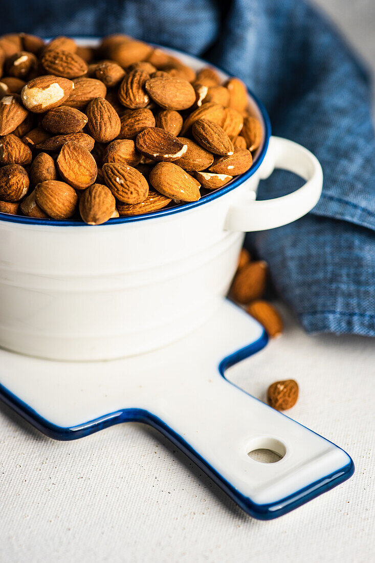 Ceramic bowl with organic almonds on white concrete background