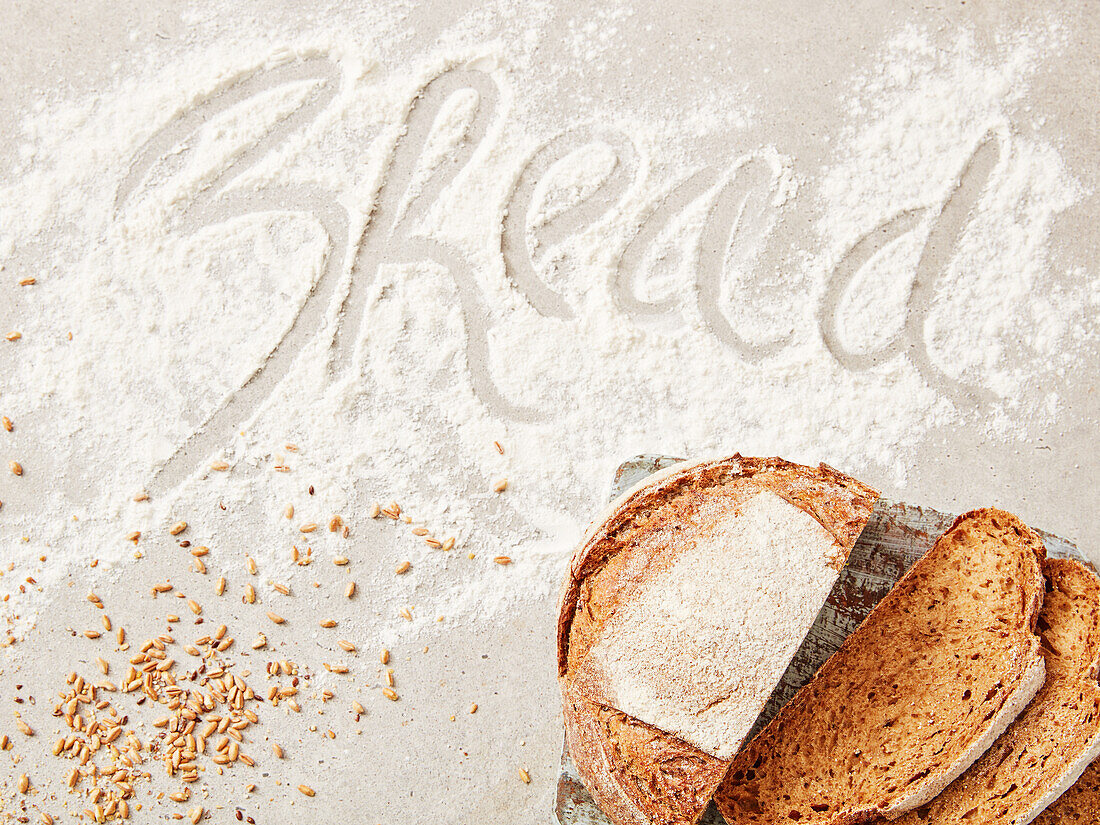 Sliced bread, grains and lettering 'Bread' in flour