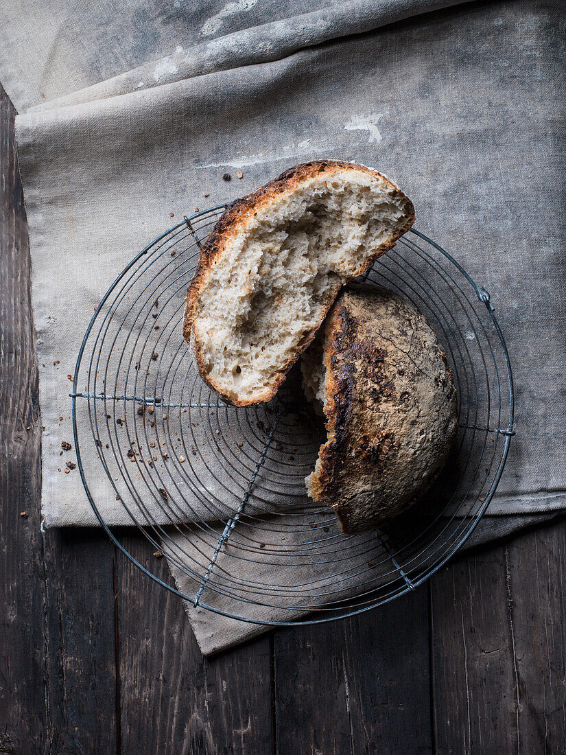 Rustic bread loaf, broken open on cooling rack