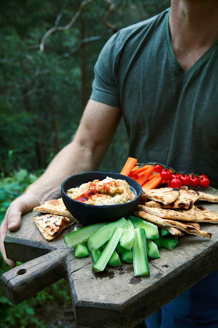 Tortilla patties, vegetables and dip on a large wooden board