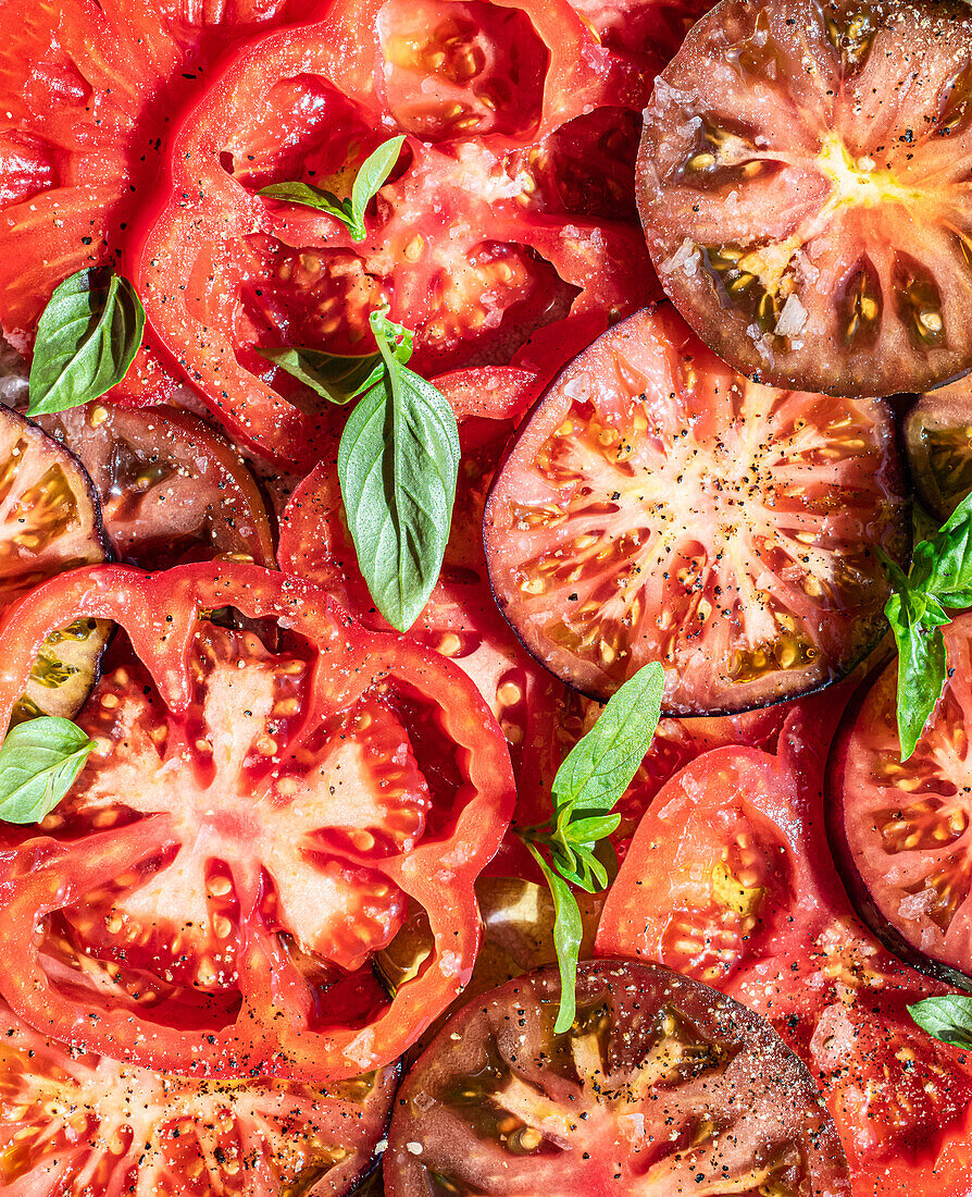 Tomatenscheiben mit frischem Basilikum (Bildfüllend)