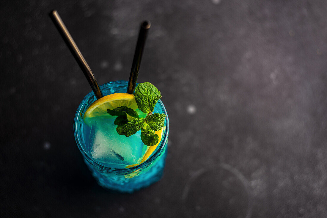 Blauer Kamikaze-Drink dekoriert mit frischer Minze und Zitronenscheibe