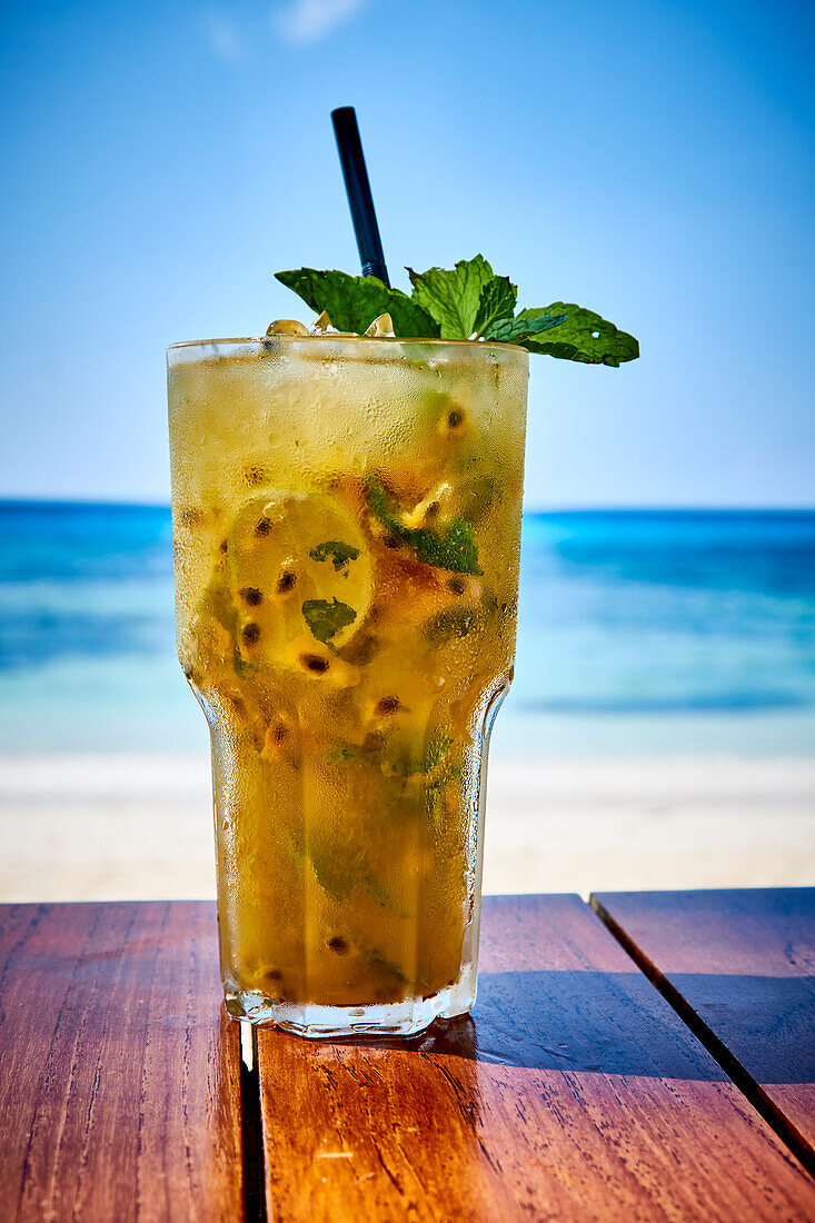 Passionsfrucht-Cocktail auf Tisch am Strand (Seychellen)