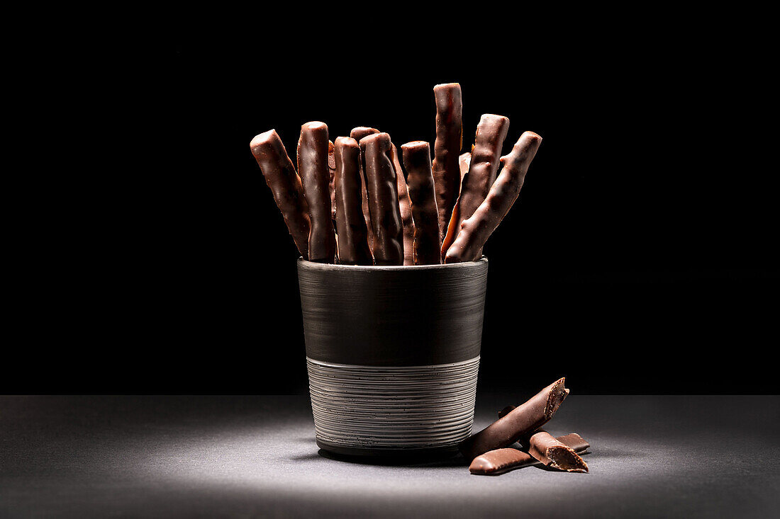 Chocolate sticks in a cup against a dark background