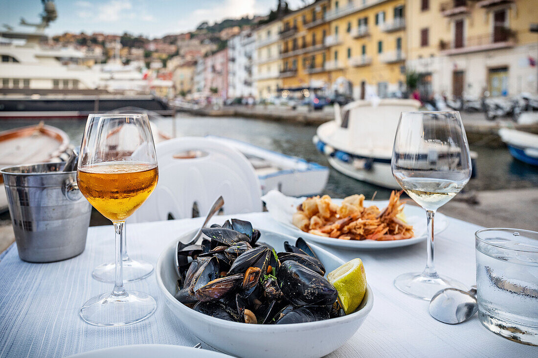 Miesmuscheln, Fritto misto und Aperitif auf gedecktem Tisch mit Hafenblick (Italien)