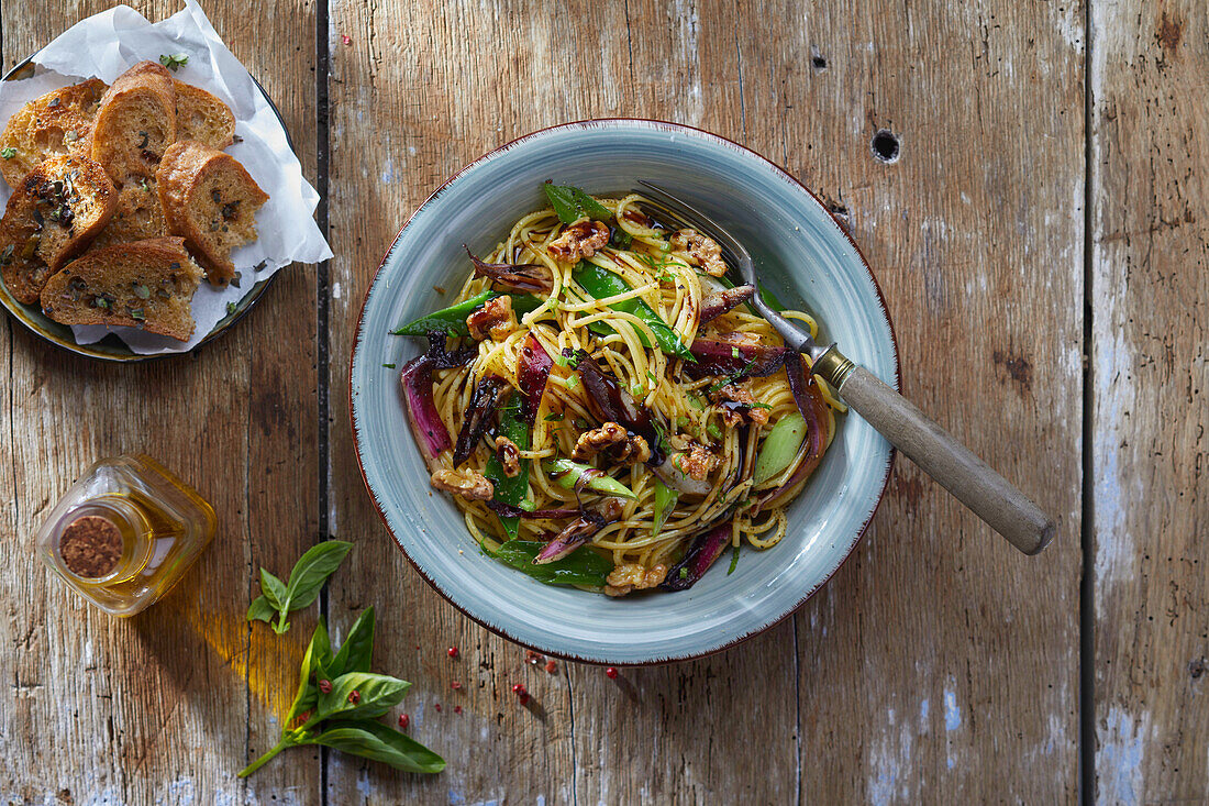 Spaghetti with fried onions, sugar snap peas and walnuts