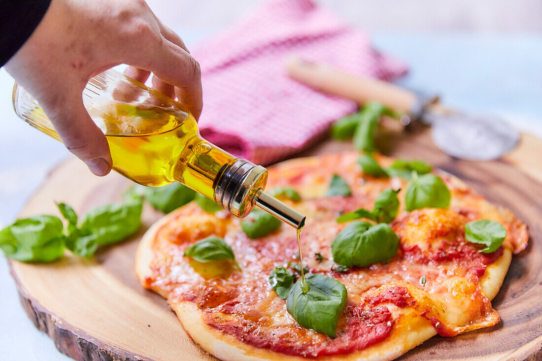 Pizza Napoli mit Olivenöl beträufeln