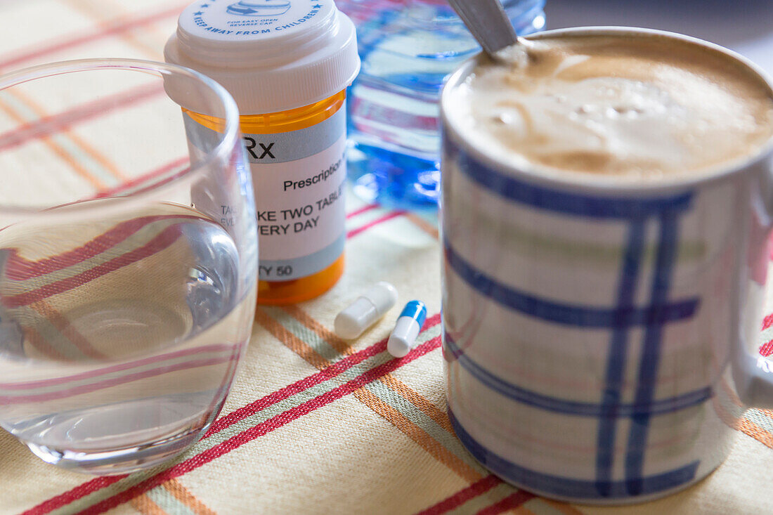 Medication next to a cup of coffee, conceptual image