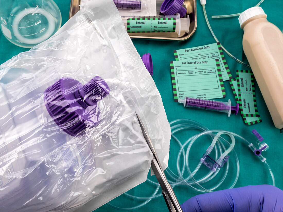 Nurse opening bottle of enteral nutrition, conceptual image