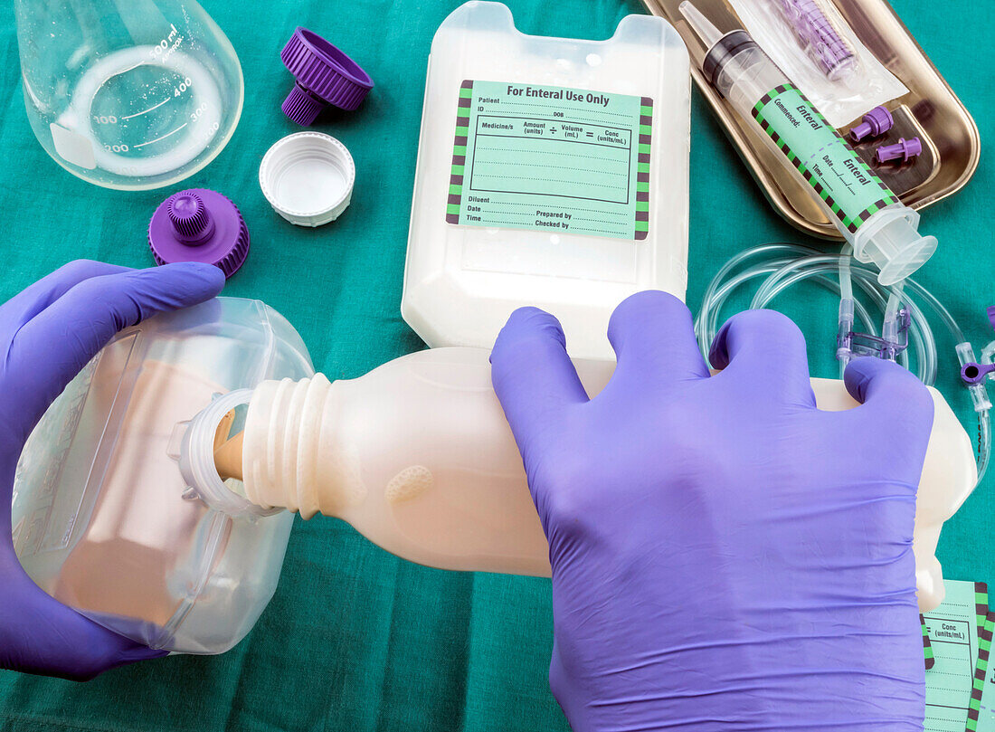 Nurse filling bottle of enteral nutrition, conceptual image