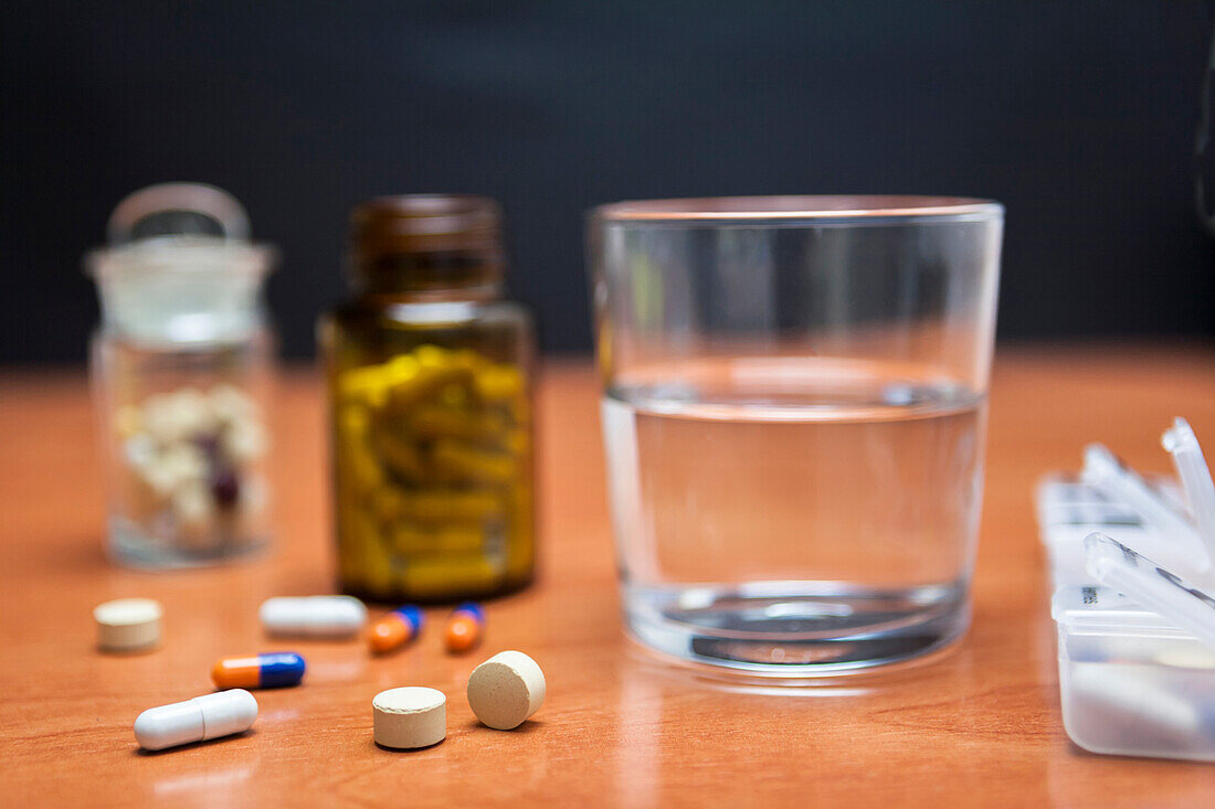 Bottle of pills along with a few pills on a wooden table