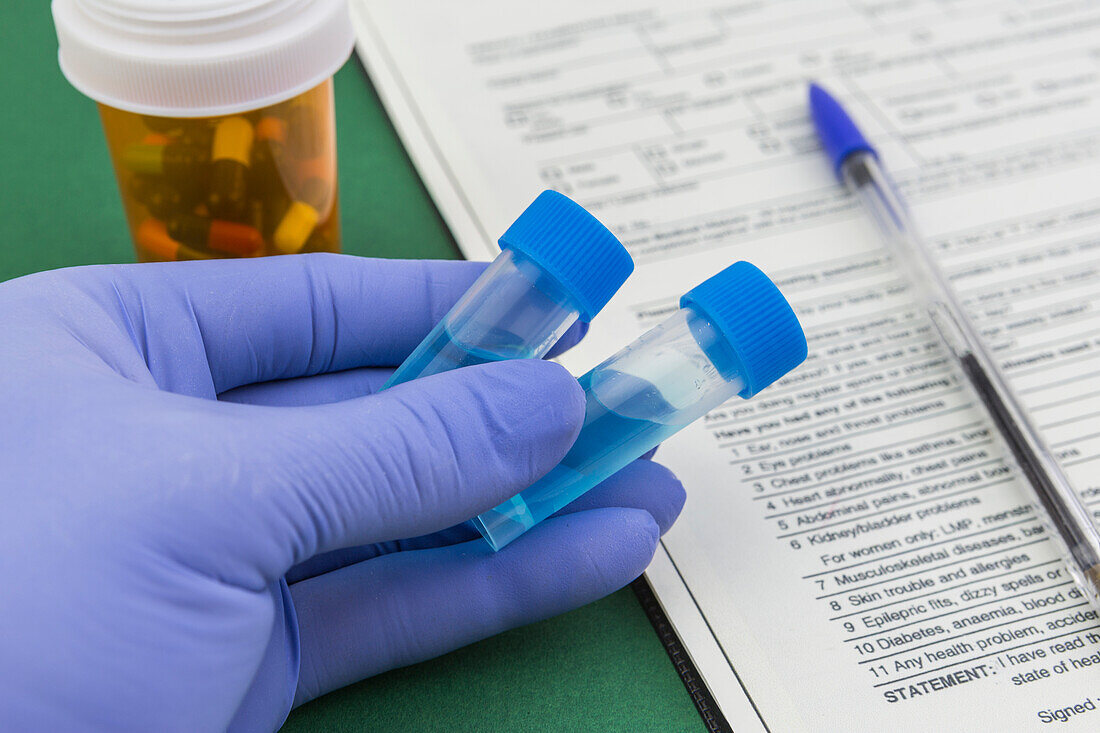 Blue latex gloved hands holding vials in a laboratory
