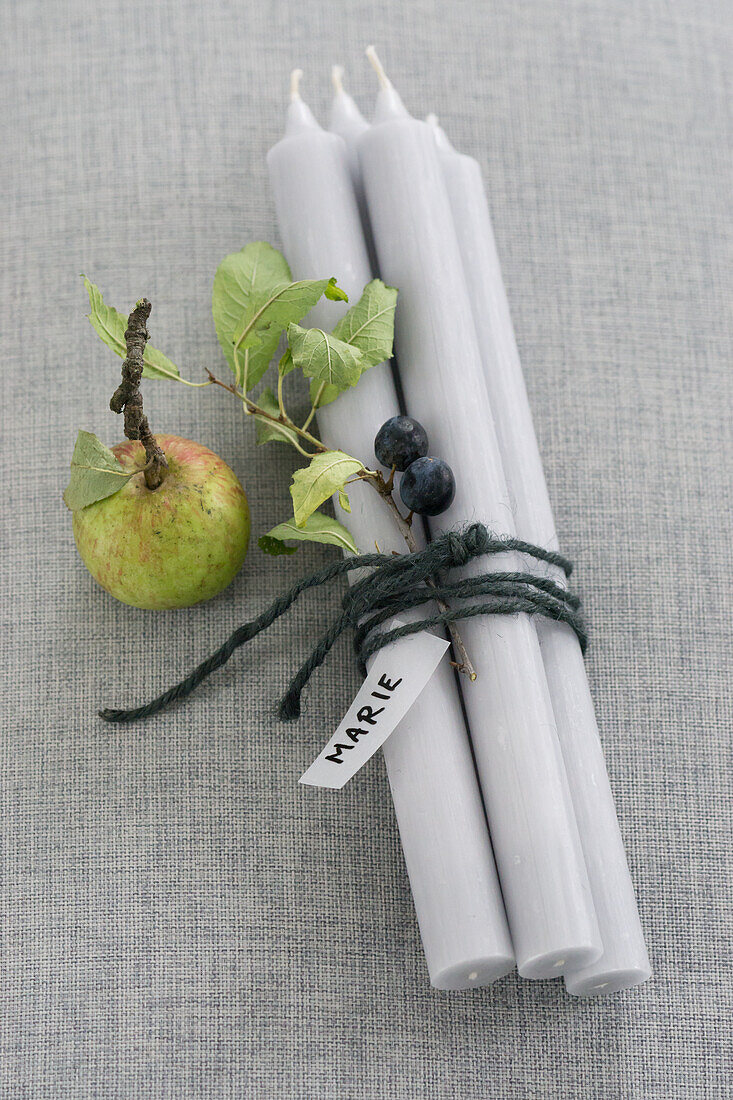 Four candles, with sloe branch, apple, and name tag