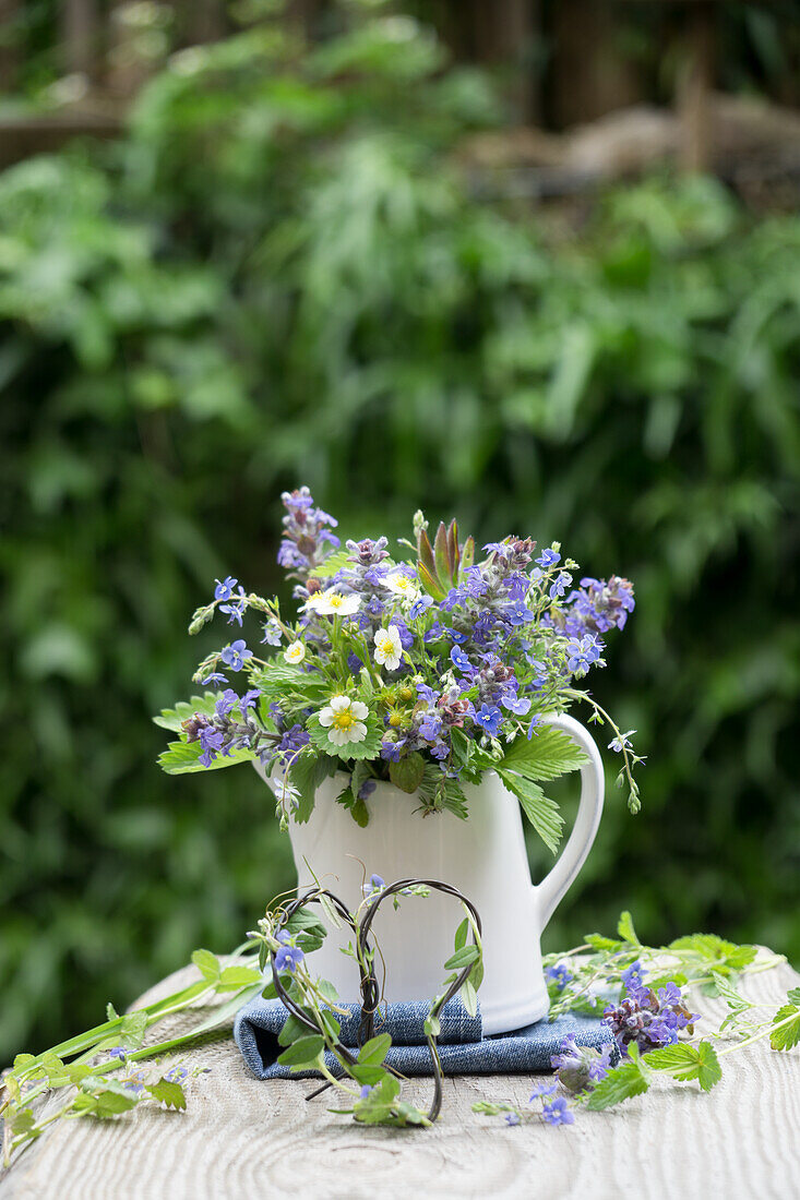 Bouquet in milk jug, of forget-me-nots (Myosotis), günsel (Ajuga) speedwell (Veronica), strawberry leaves