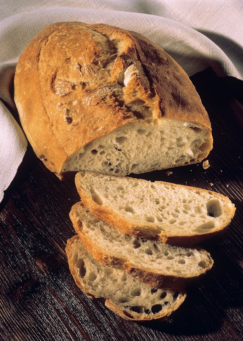 Ein angeschnittenes knuspriges Weizenbrot & Brotscheiben