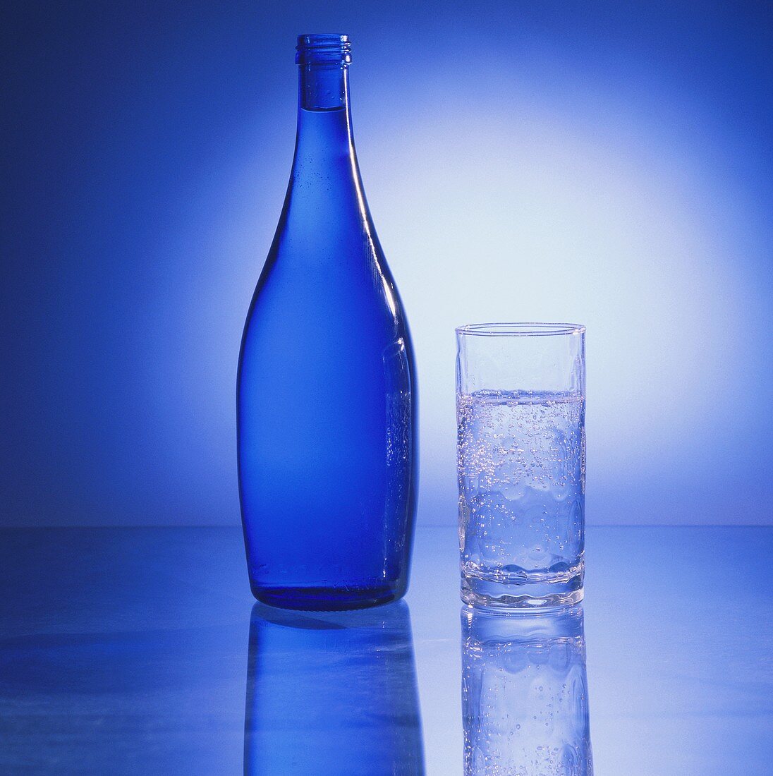Eine blaue Wasserflasche & ein Glas Mineralwasser