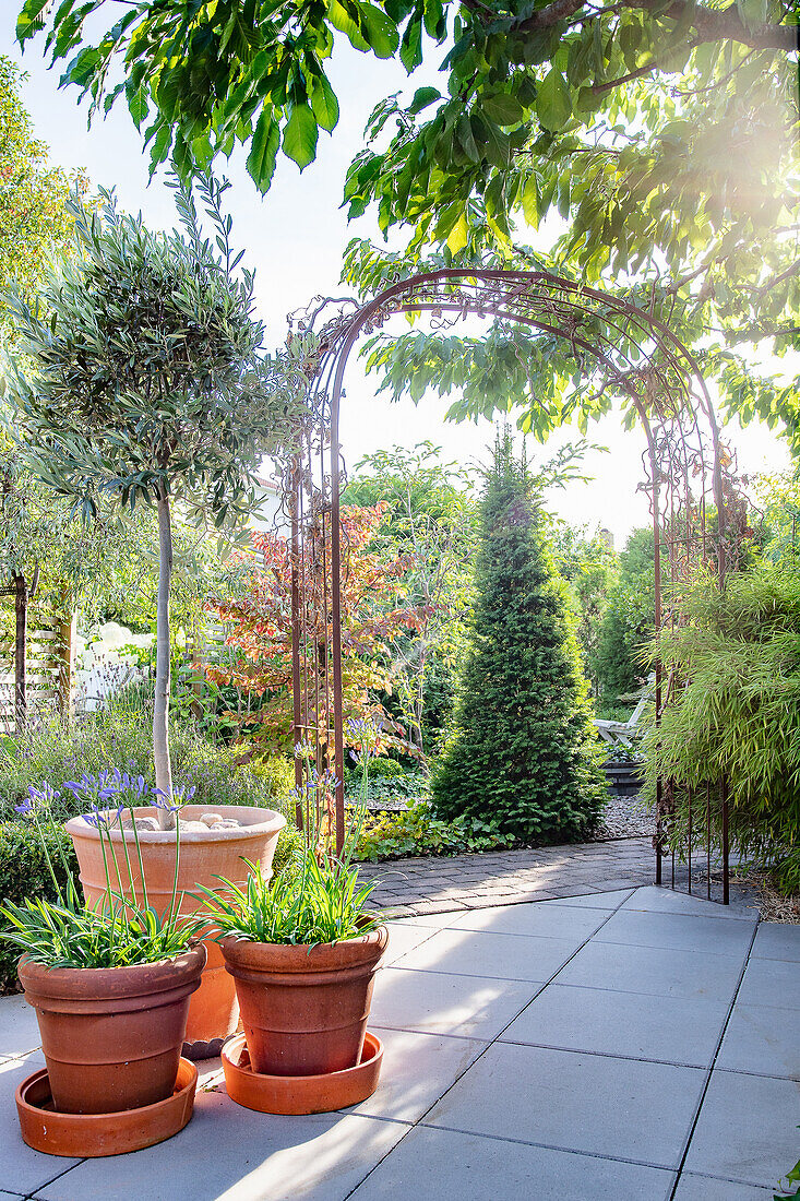 Blick von der Terrasse durch das Portal aus Gusseisen auf den Garten