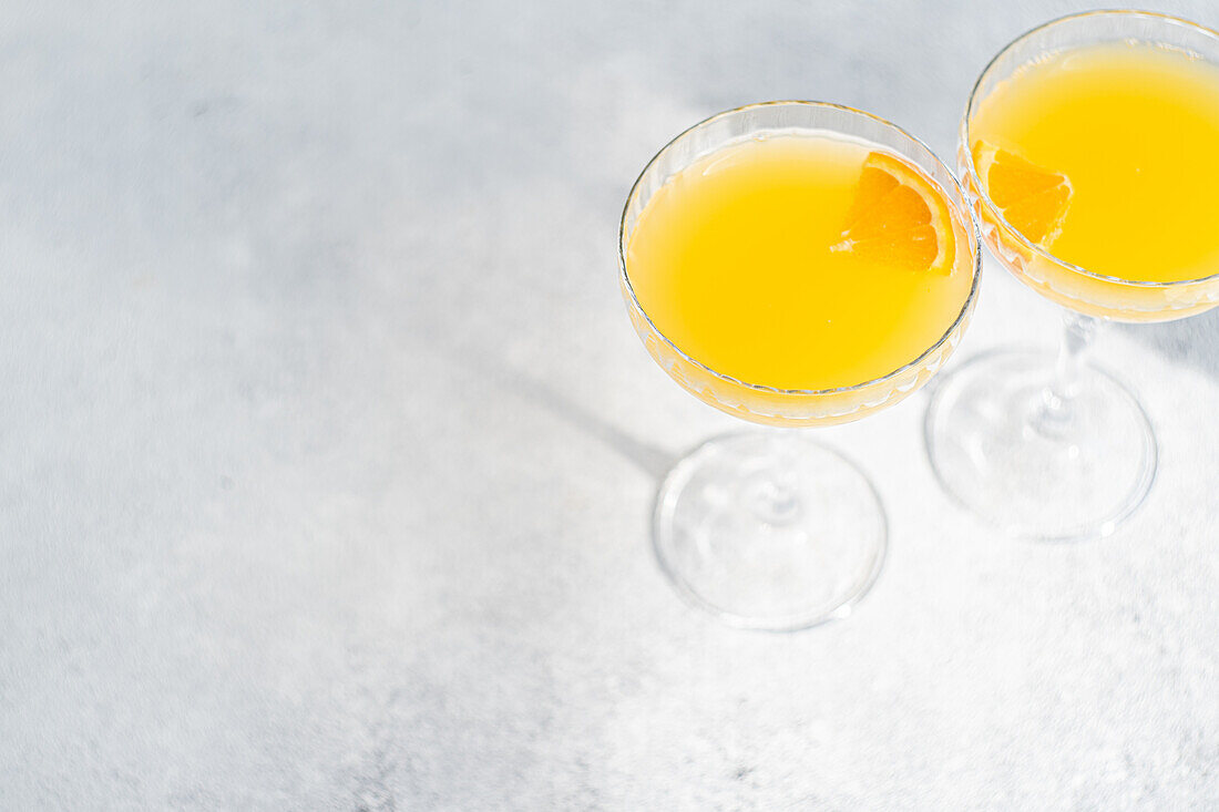 Glass of mimosa cocktail on stone background in sunny day