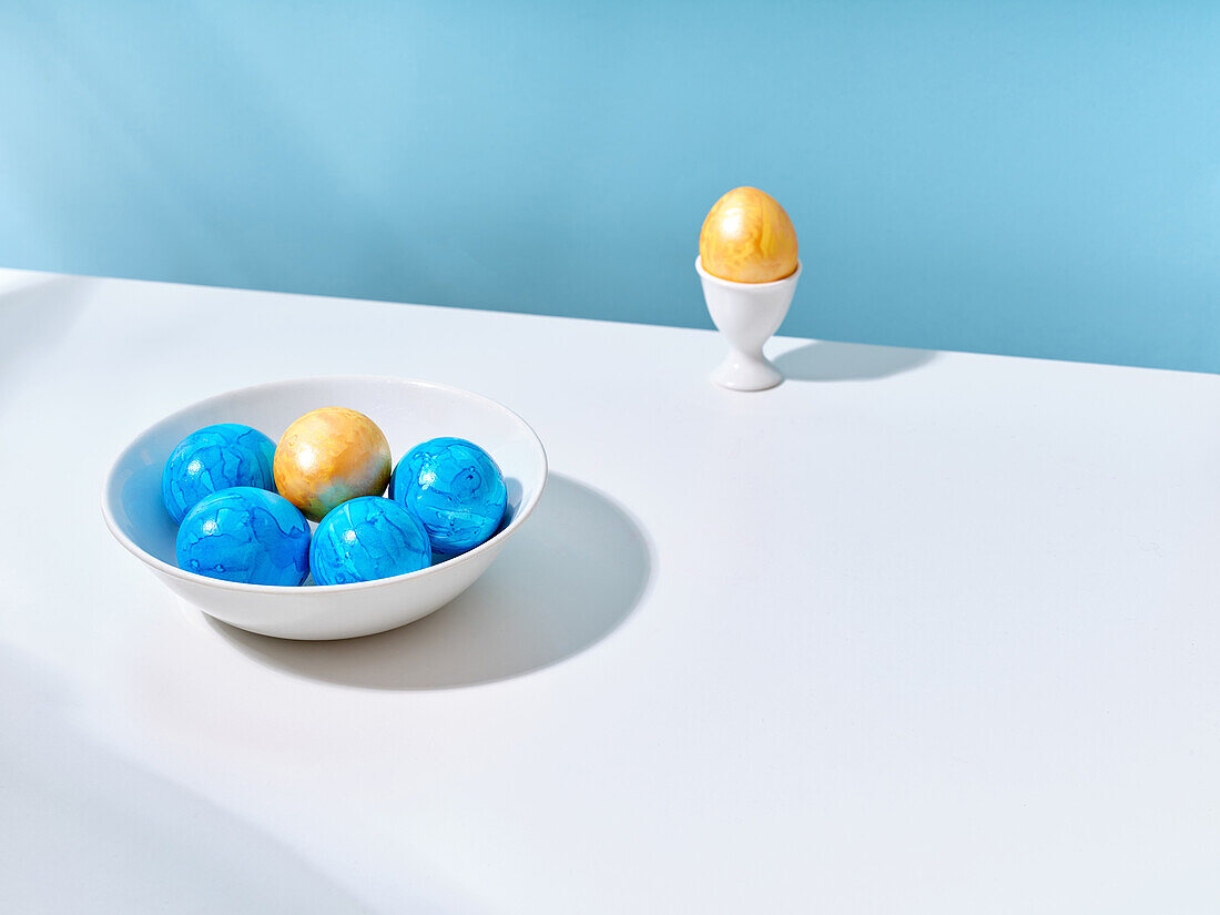 Creative layout with colored blue and golden easter eggs on bright background
