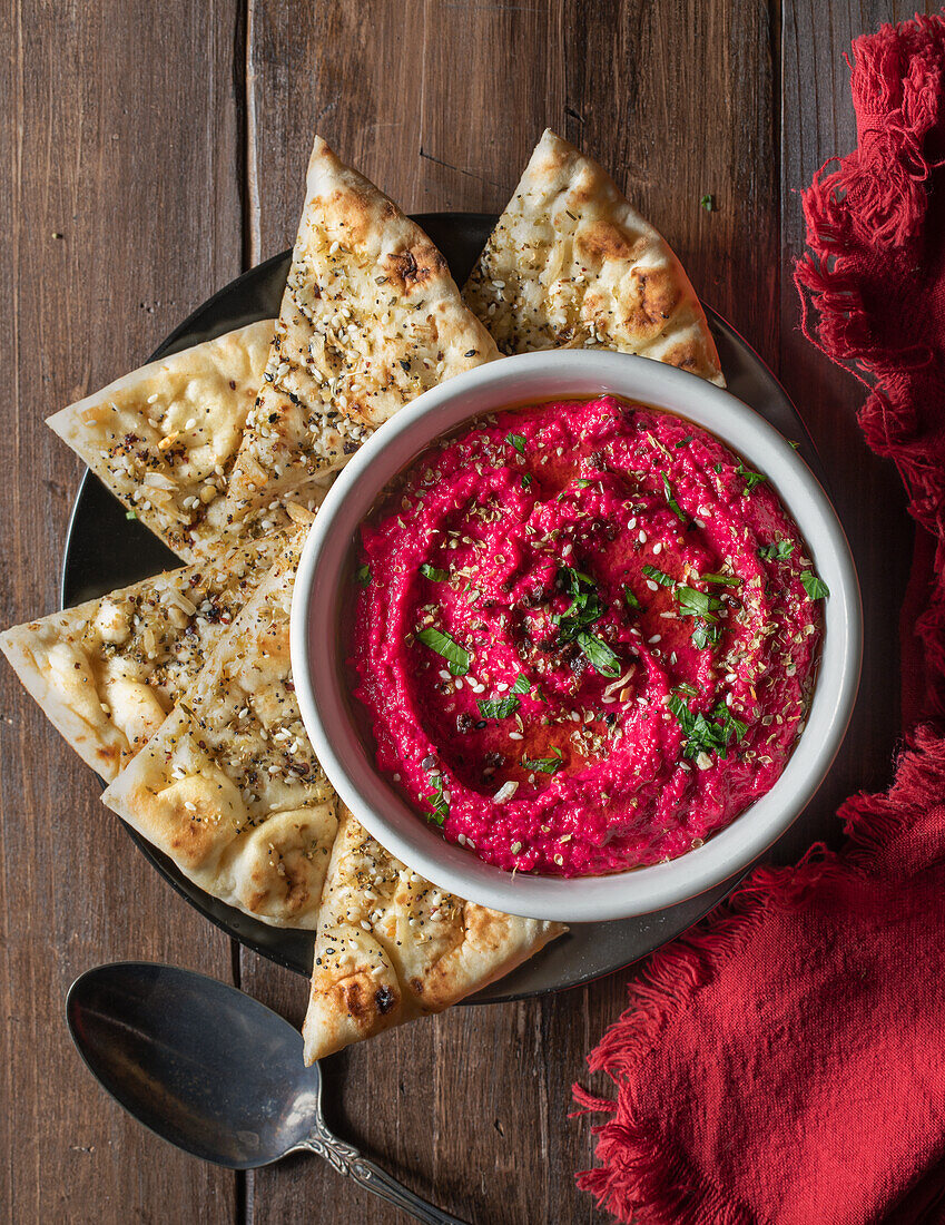 Rote-Bete-Hummus und geschnittene Fladenbrotstücke mit Zatar-Gewürz