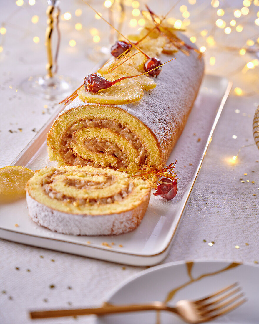 Festive sponge cake roll with jam and nut filling, candied lemon and spinning sugar