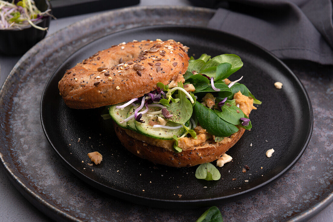 Bagel with vegan lentil spread, lamb's lettuce, cucumber, walnuts and sprouts