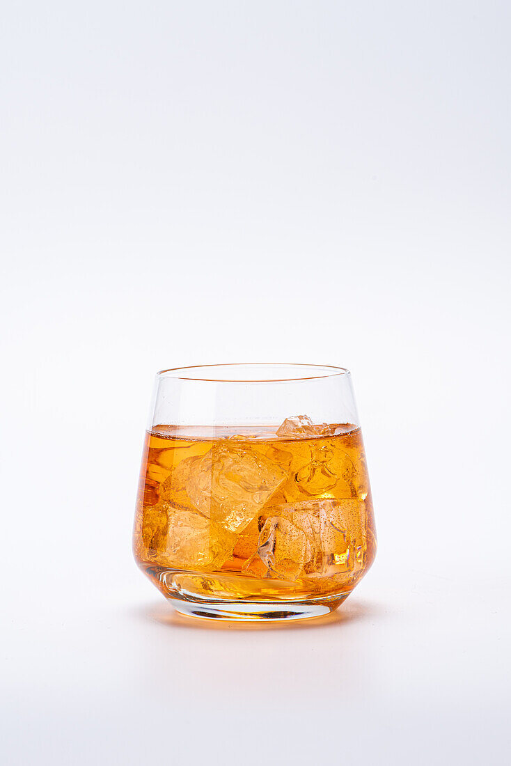 Ein Glas Whisky mit Eiswürfeln vor weißem Hintergrund