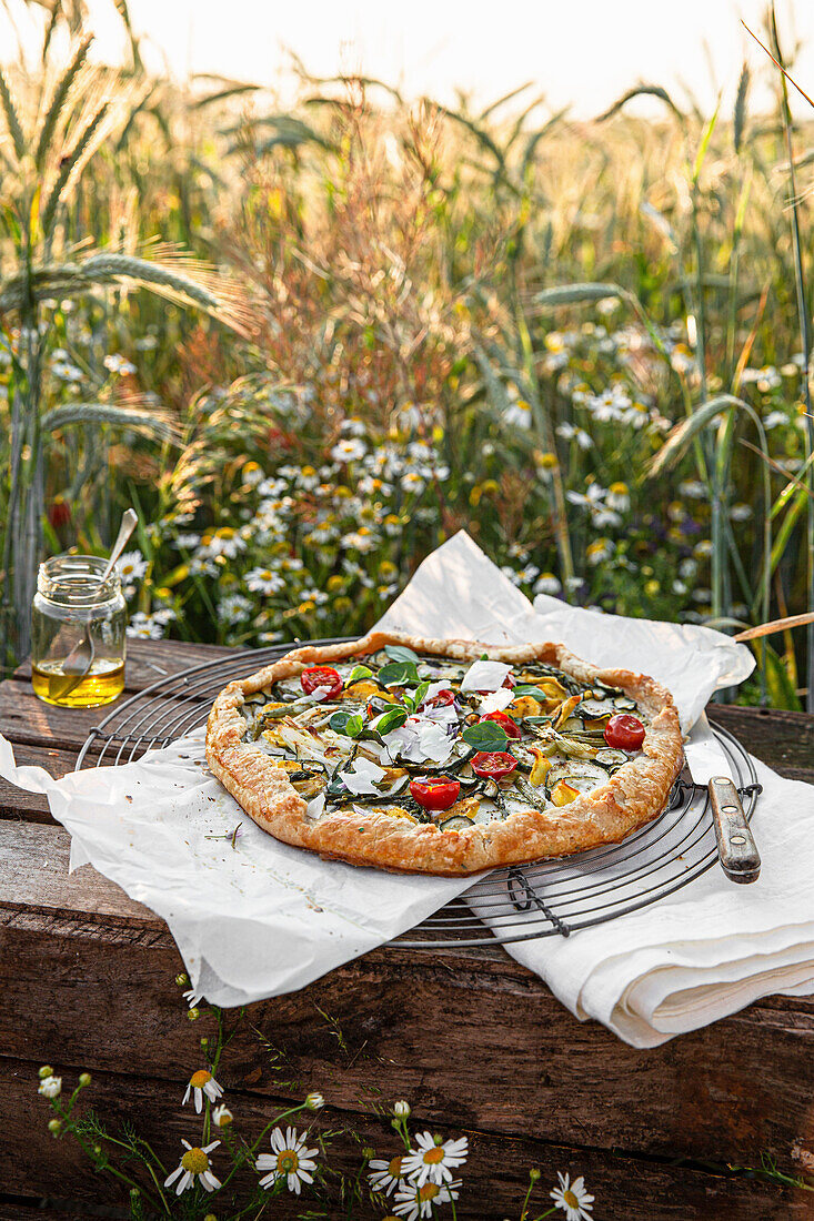 Bunte Gemüsepizza auf rustikalem Holztisch im Freien