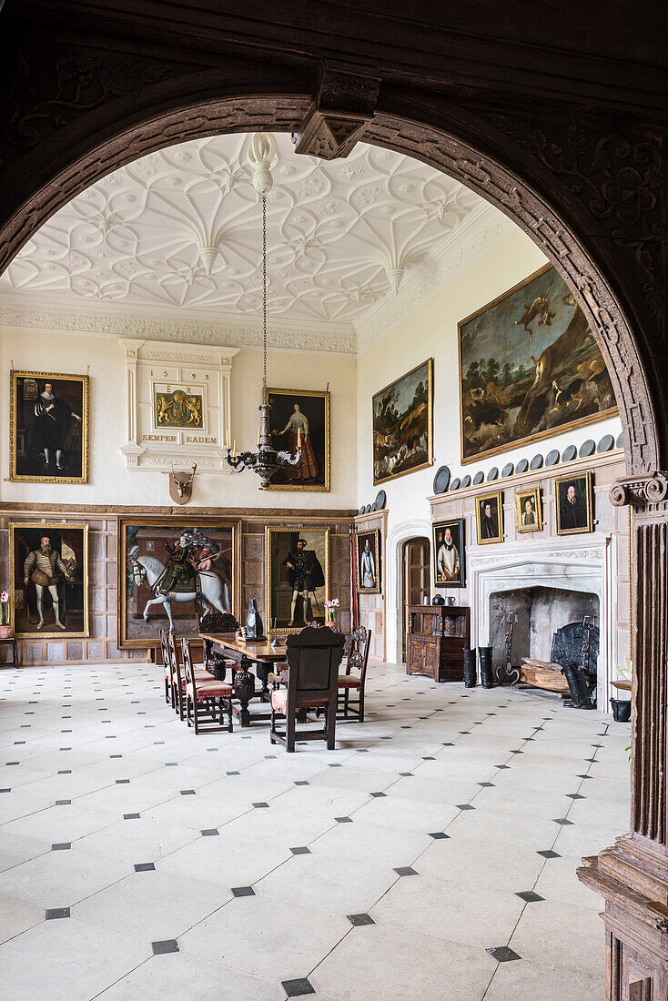 Blick durch dekorativen Torbogen aus Holz in restaurierten Bankettsaal mit hoher Decke