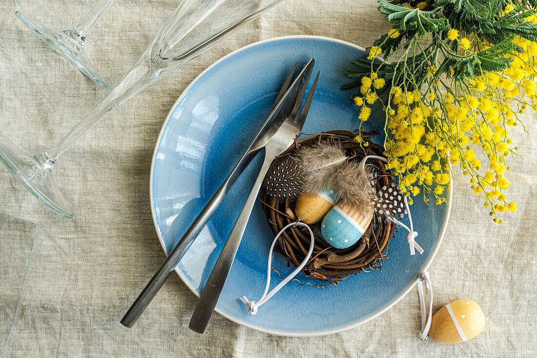 Festive table setting for Easter holiday dinner with bright yellow mimosa flowers on concrete table