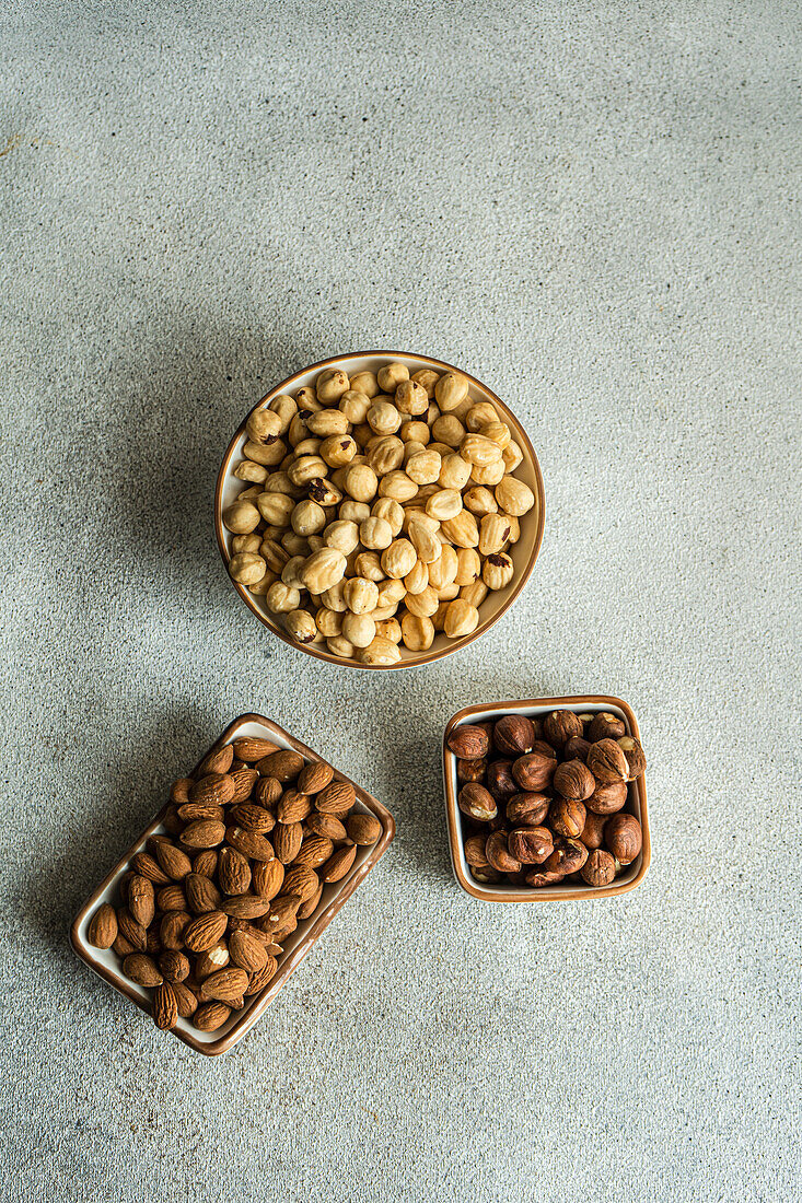 Assortment of organic nuts in wooden bowls on rustic background