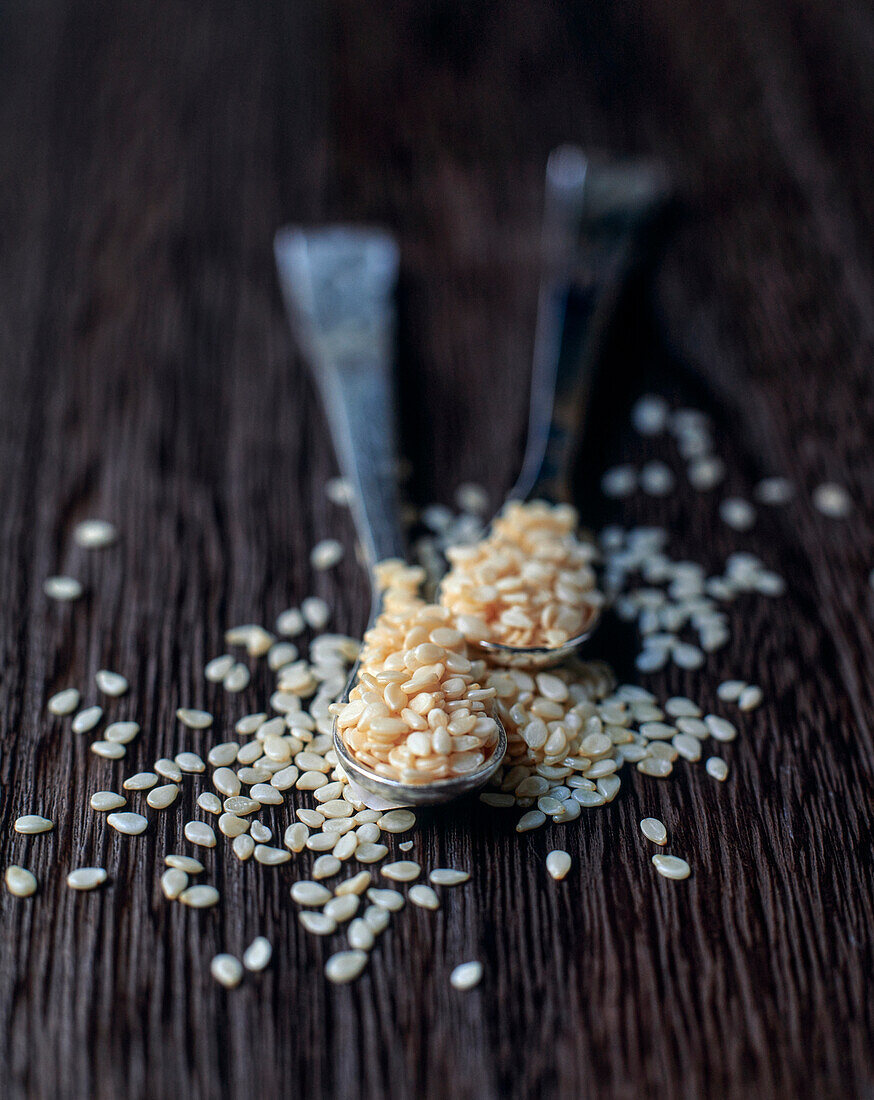 White sesame seeds on spoons and wooden base
