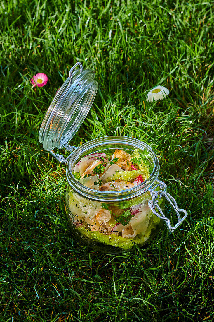 Caesar salad in a glass jar on the grass