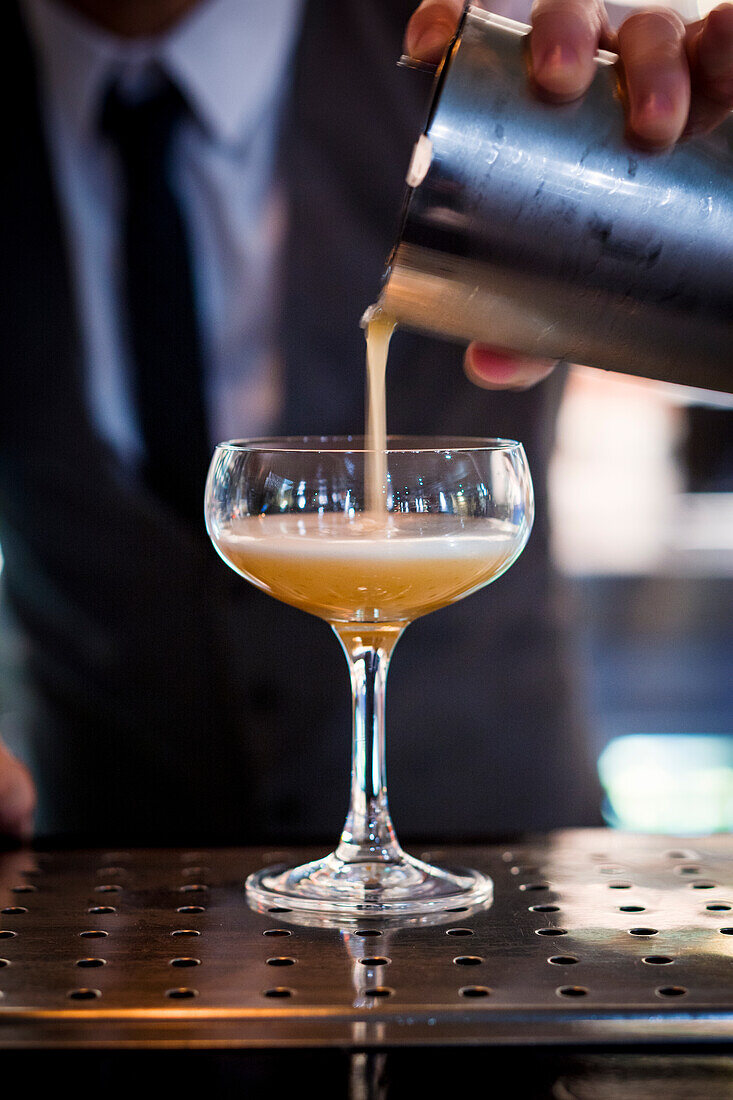 Barkeeper schenkt einen Cocktail ein