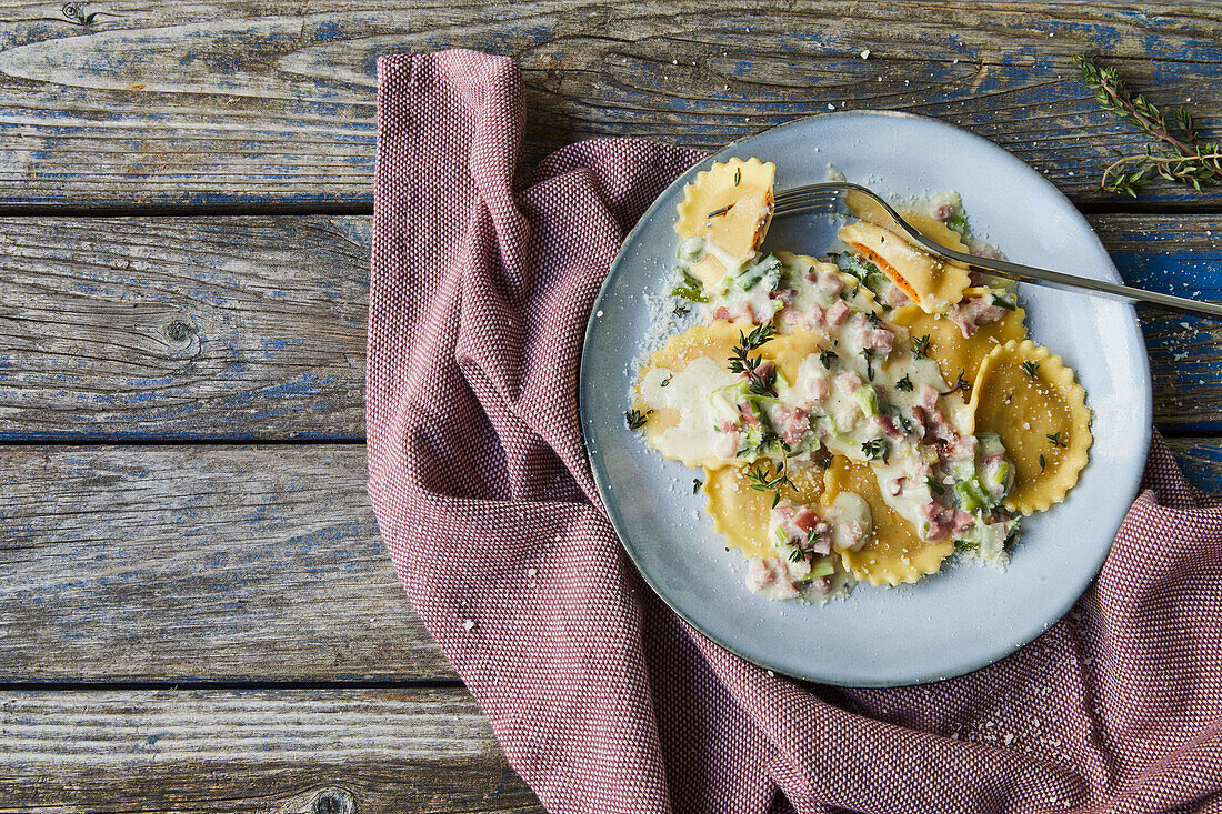 Vegetable ravioli with cheese sauce and ham cubes