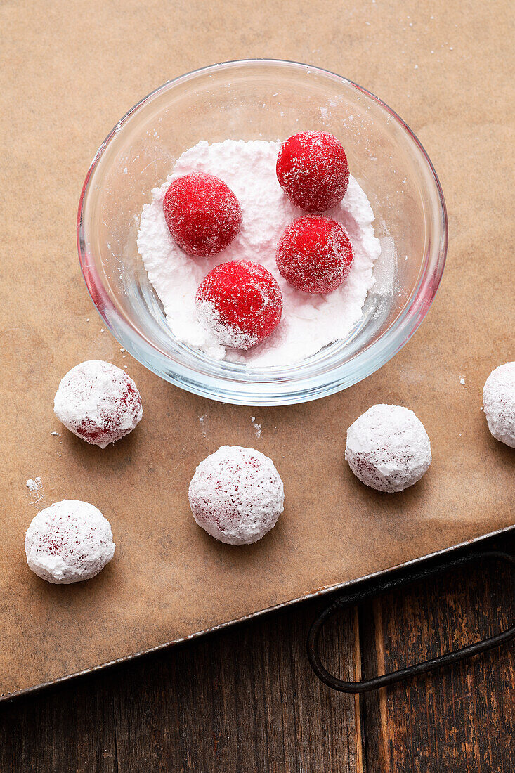 Rolling raspberry crinkles in powdered sugar