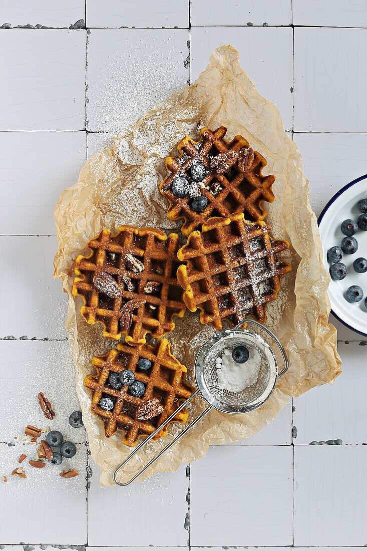 Spicy pumpkin waffles with fresh blueberries and dusted with powdered sugar