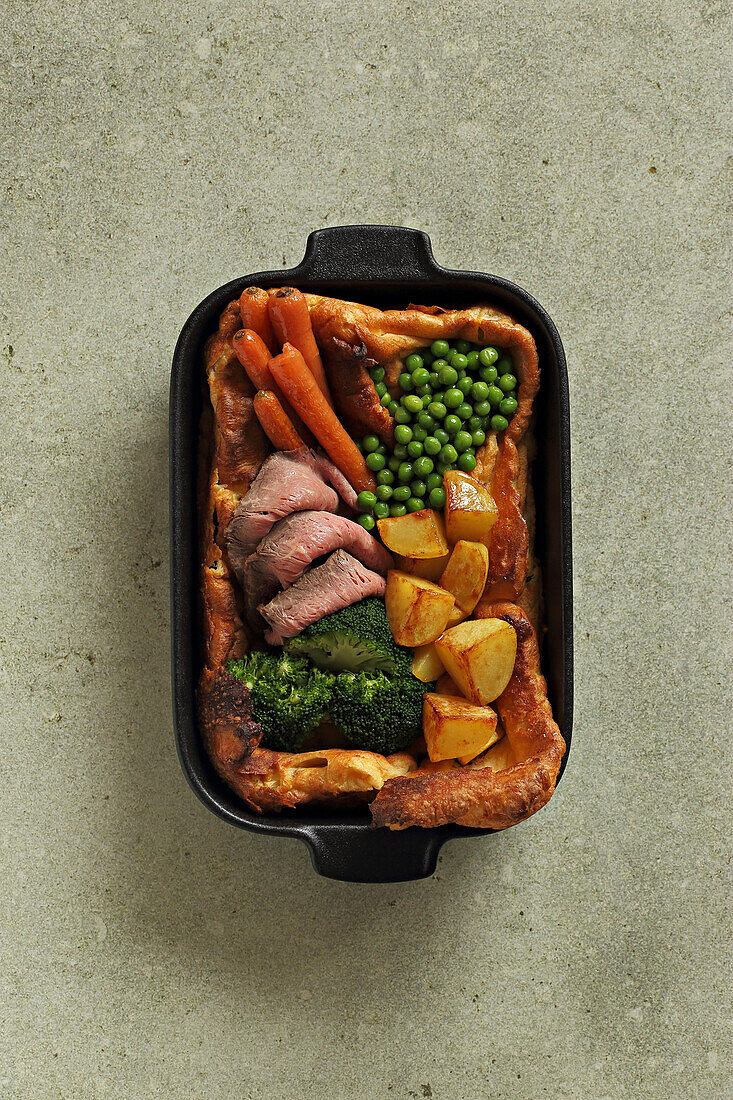 Giant Yorkshire pudding with carrots, roast beef, potatoes, and broccoli