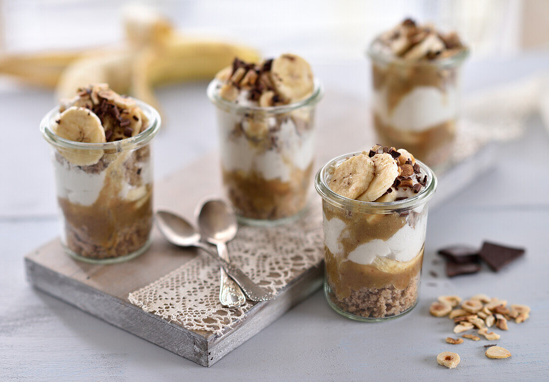 Vegan hazelnut, coconut, and banoffee desserts in glasses with chocolate chips