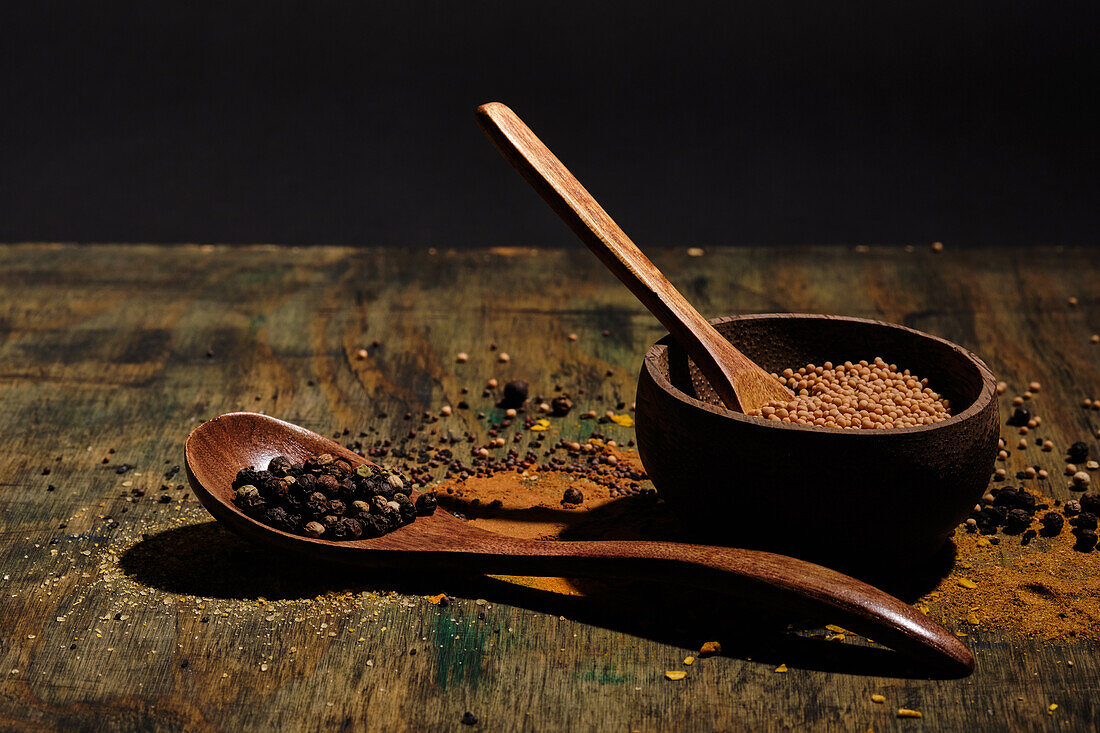 Pepper and coriander with wooden bowl and wooden spoon with spices on wood