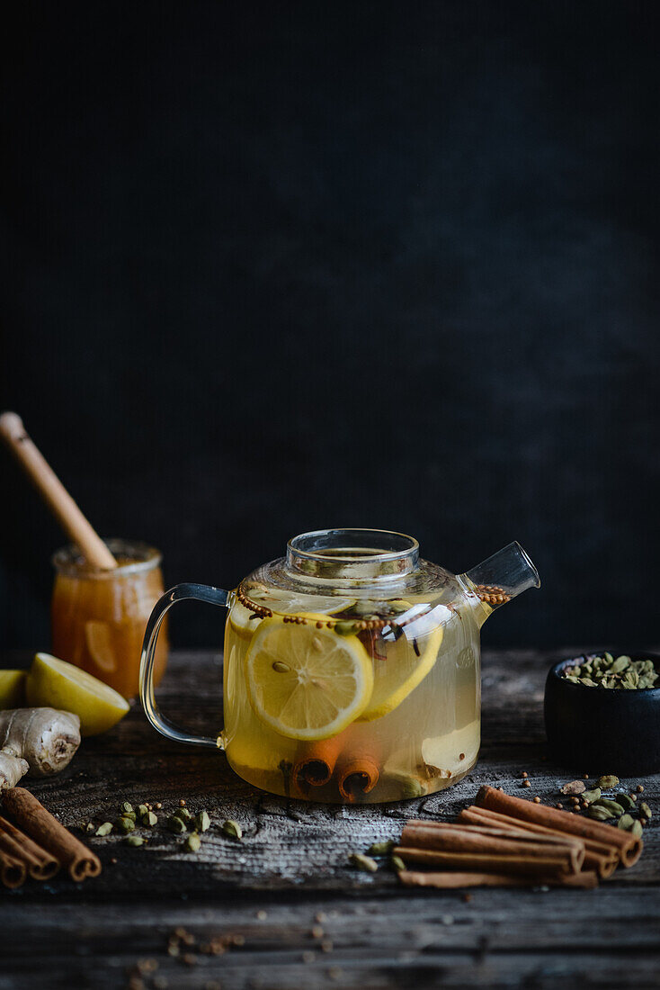 Spicy winter tea with lemon, cinnamon and cardamom in glass teapot