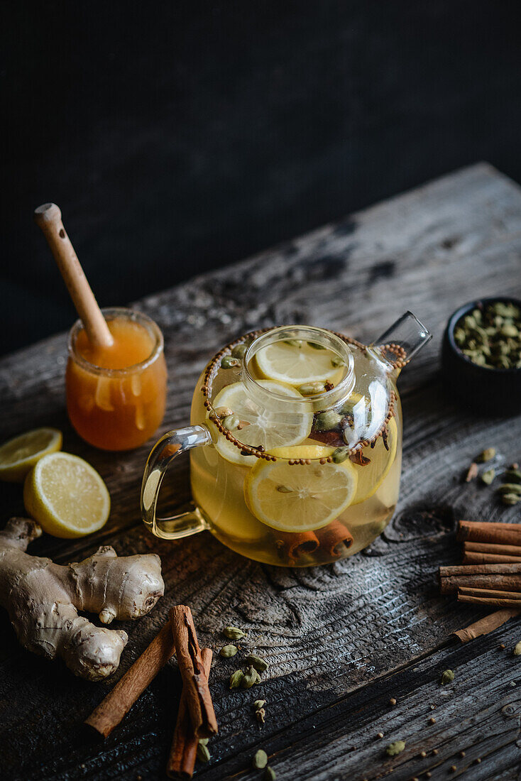 Spicy winter tea with lemon, cinnamon and cardamom in a glass teapot