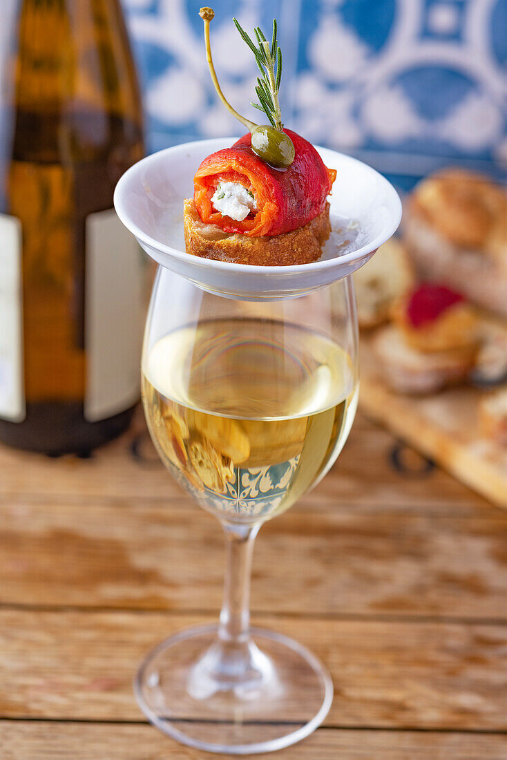 Ein Glas Weißwein und Pincho mit gerösteter Paprika und Schafsmilch-Frischkäse