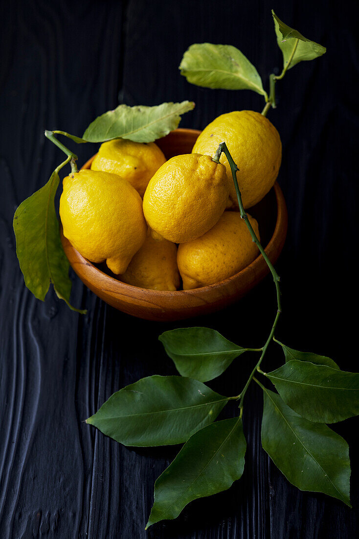 Fresh lemons with leaves in a wooden bowl
