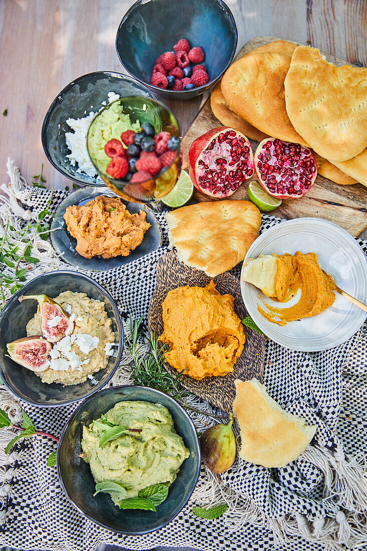 Hummus in different variations with pita bread, berries, and pomegranate