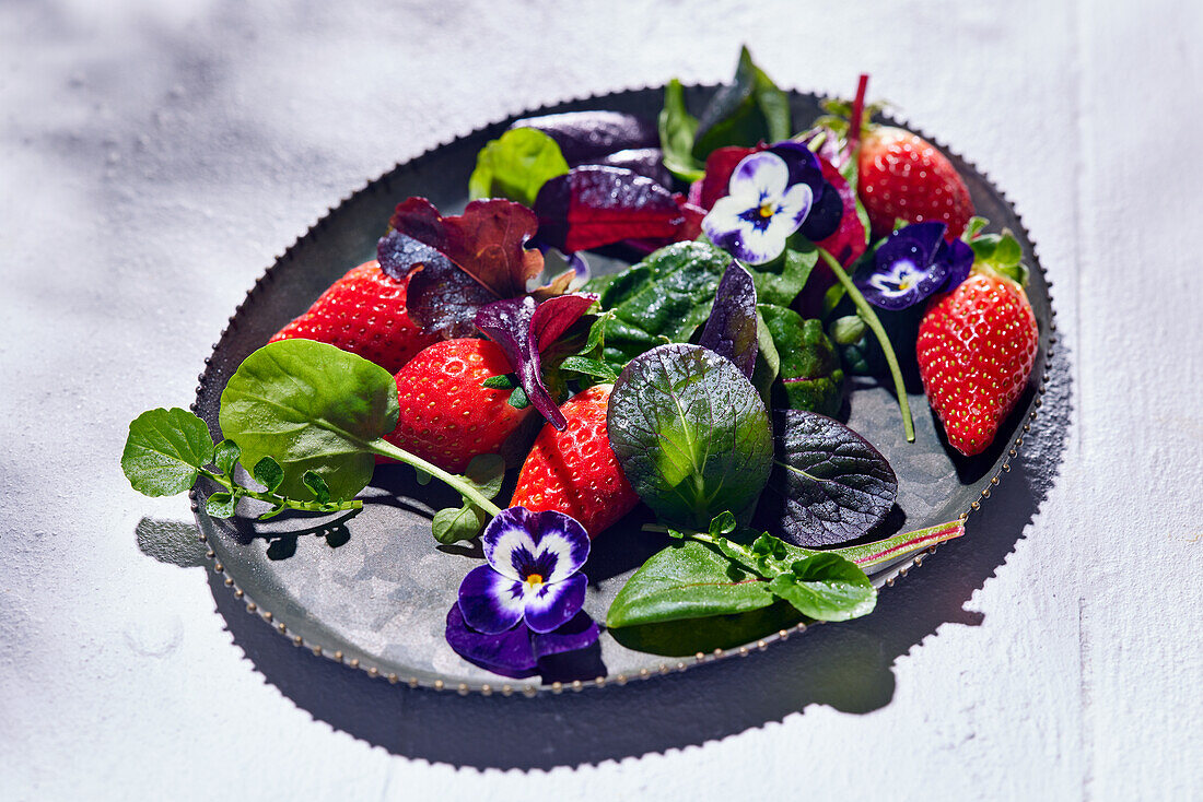 Wild herb salad with strawberries and edible flowers